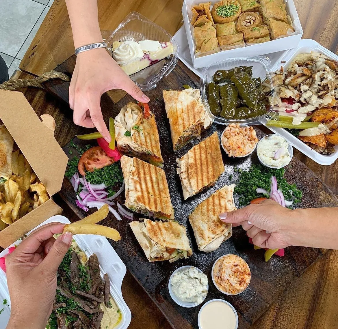 Hands sharing Johnny’s wraps, dips and sides around a table